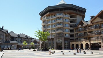 Un hotel de varios pisos con patio central, balcones y una cafetería.