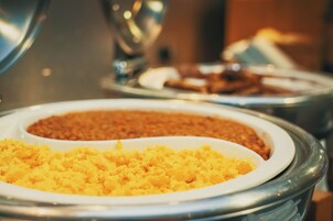 Buffet com diversos pratos, incluindo purê de batatas e um prato marrom, possivelmente um ensopado ou gratinado.