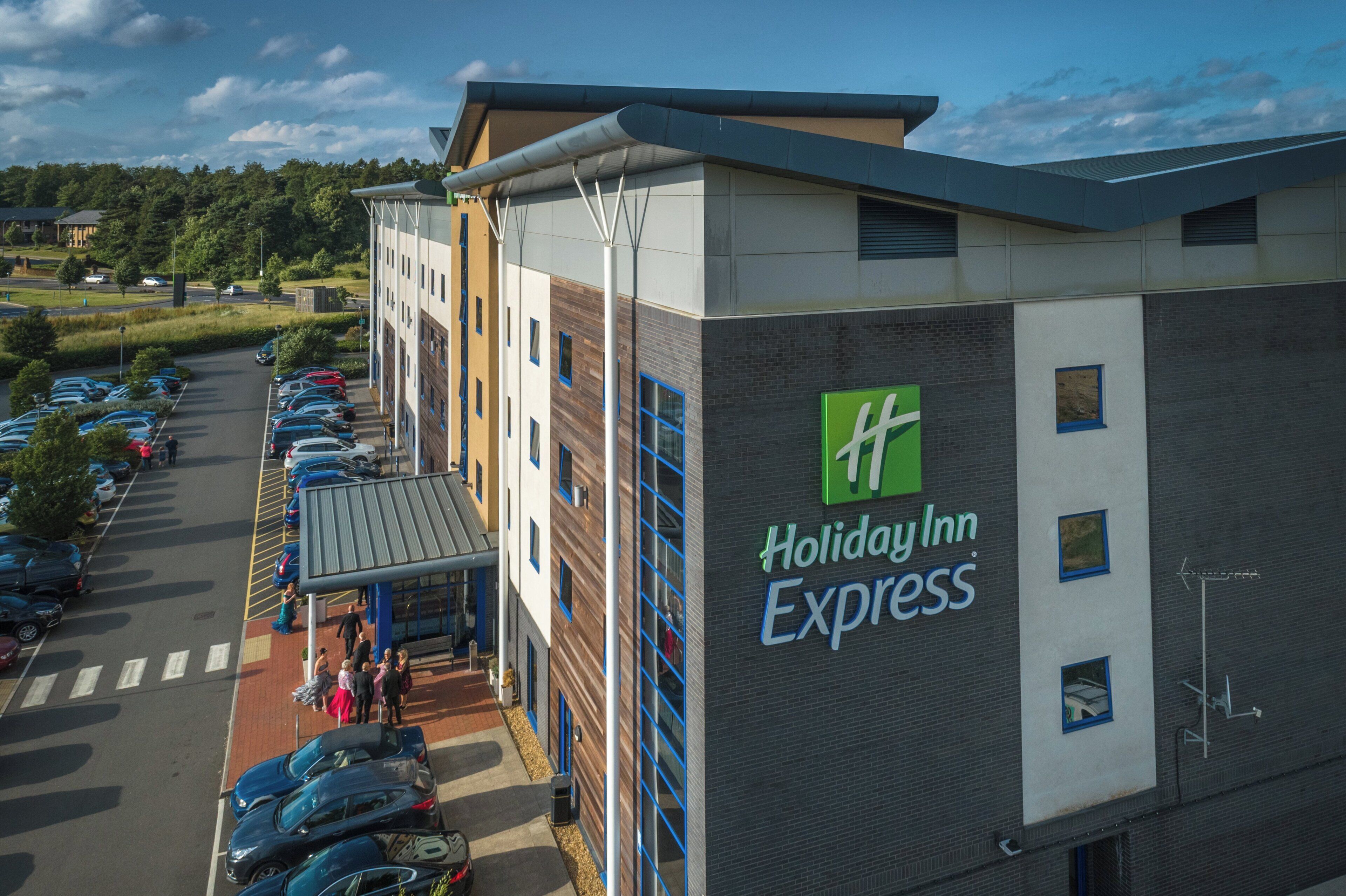 Edificio de Holiday Inn Express con estacionamiento y una pasarela cubierta.