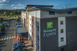 Edificio de Holiday Inn Express con estacionamiento y una pasarela cubierta.