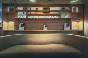 Un interior moderno con un sofá, estanterías de madera con adornos y dos lámparas de pie.