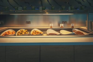 Un bufé con diversas opciones de comida, incluyendo frutas, yogur y granola.
