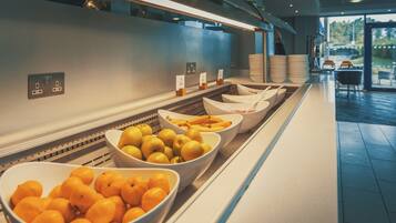 A buffet area with bowls of fruit and a self-service station.