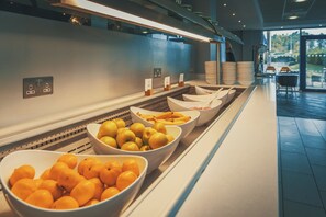 Un área de bufé con cuencos de fruta y una estación de autoservicio.