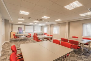 A conference room with multiple tables and chairs, a projector, and a screen. - Holiday Inn Express Kettering by IHG (Kettering)