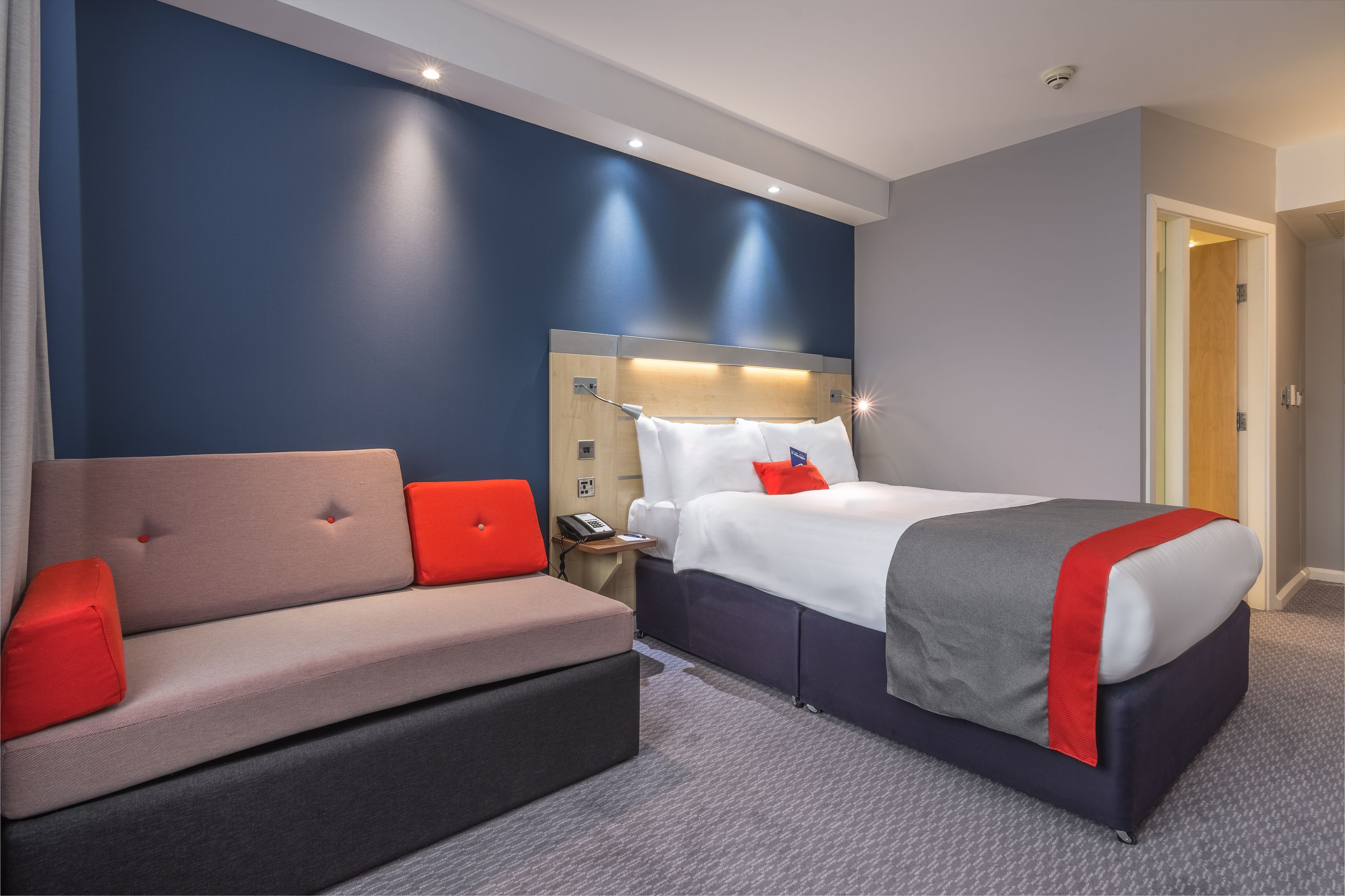 A hotel room with a bed, a sofa, and a nightstand.
