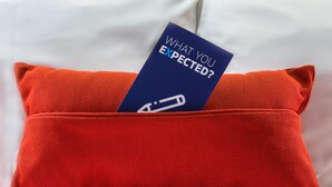 A red pillow with a tag that reads "WHAT YOU EXPECTED?" - Holiday Inn Express Kettering by IHG (Kettering)