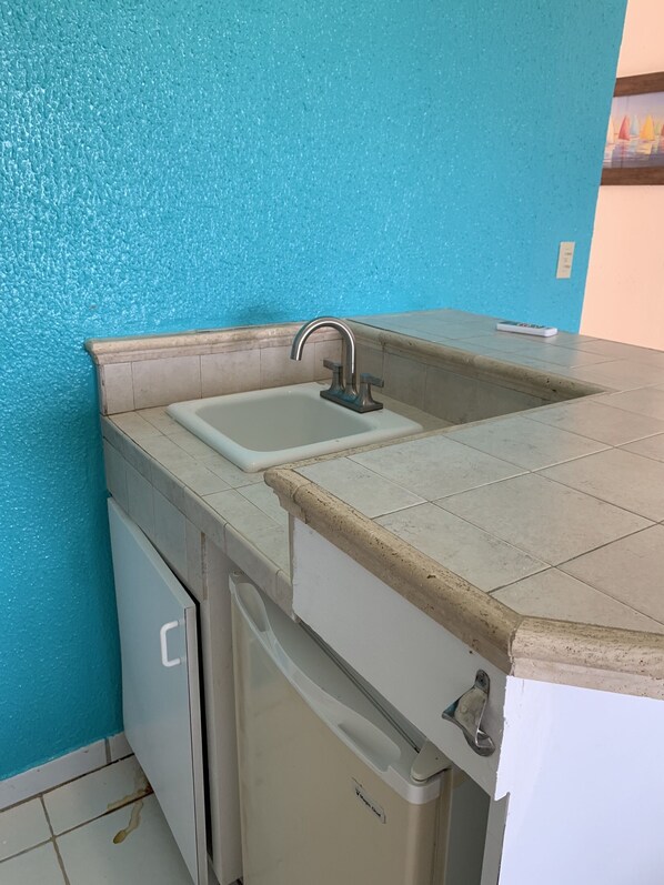 A kitchen with a sink, a dishwasher, and a countertop. - Flamboyan on the Bay Resort and Villas (St. Thomas)