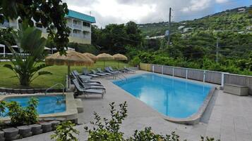 Una piscina al aire libre, sillones reclinables de piscina
