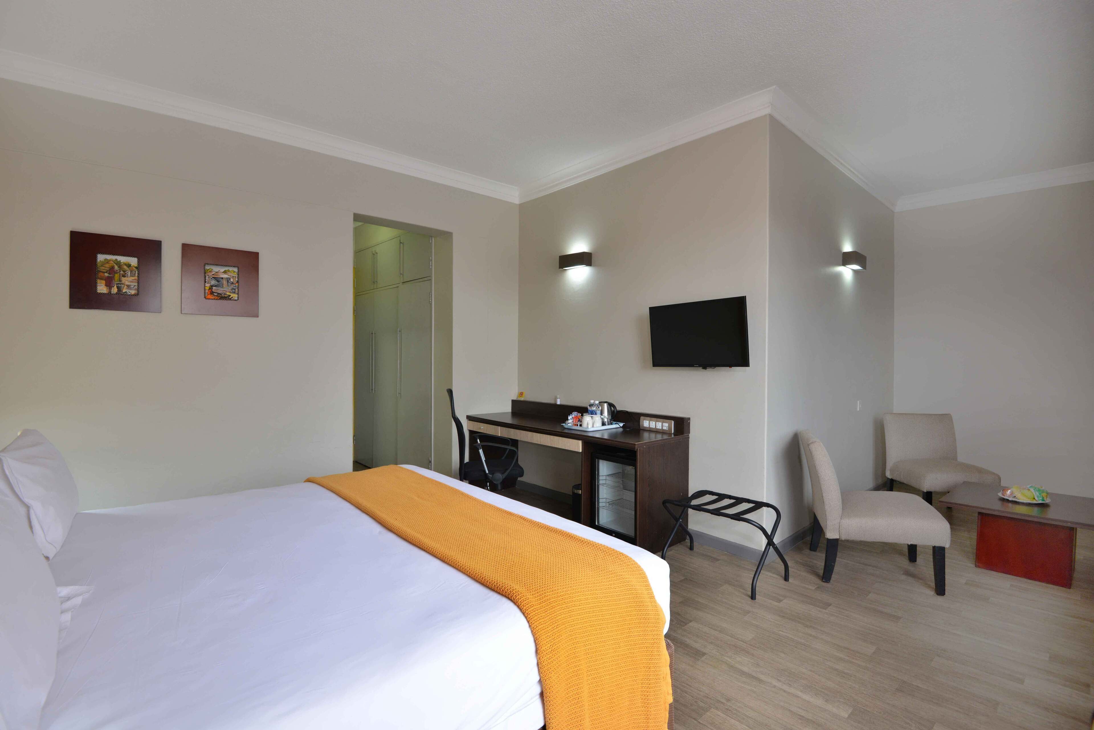 Ein Hotelzimmer mit Bett, Schreibtisch, Stuhl, Fernseher und zwei Wandleuchten.
