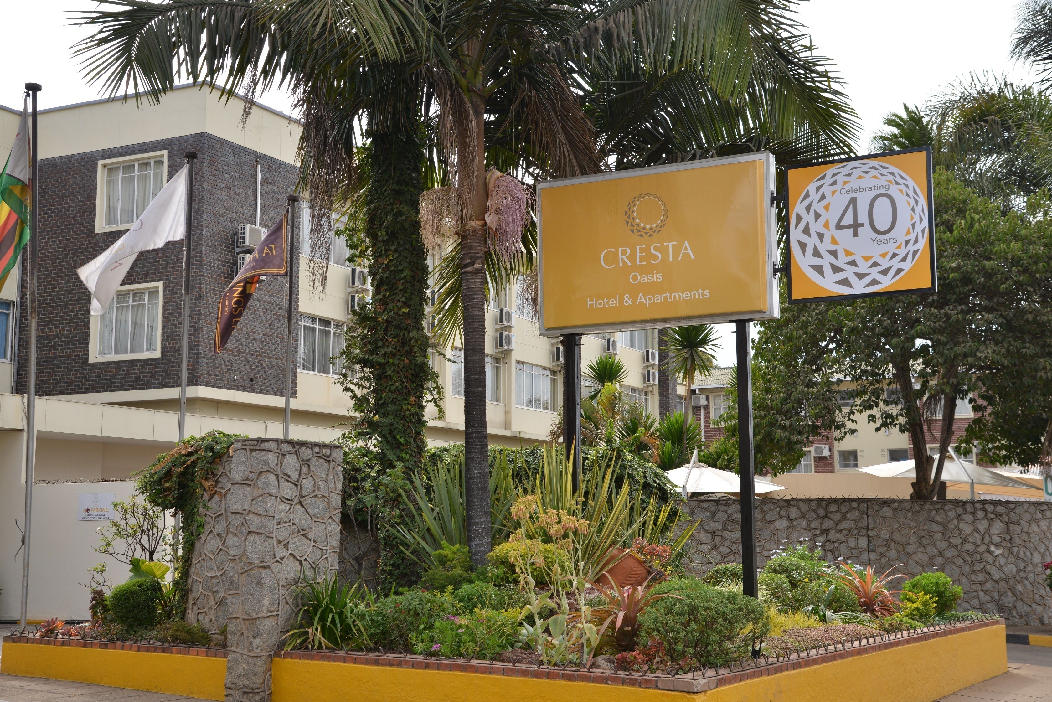 A hotel sign with "CRESTA Oasis Hotel & Apartments" and a "40 Years" celebration plaque.