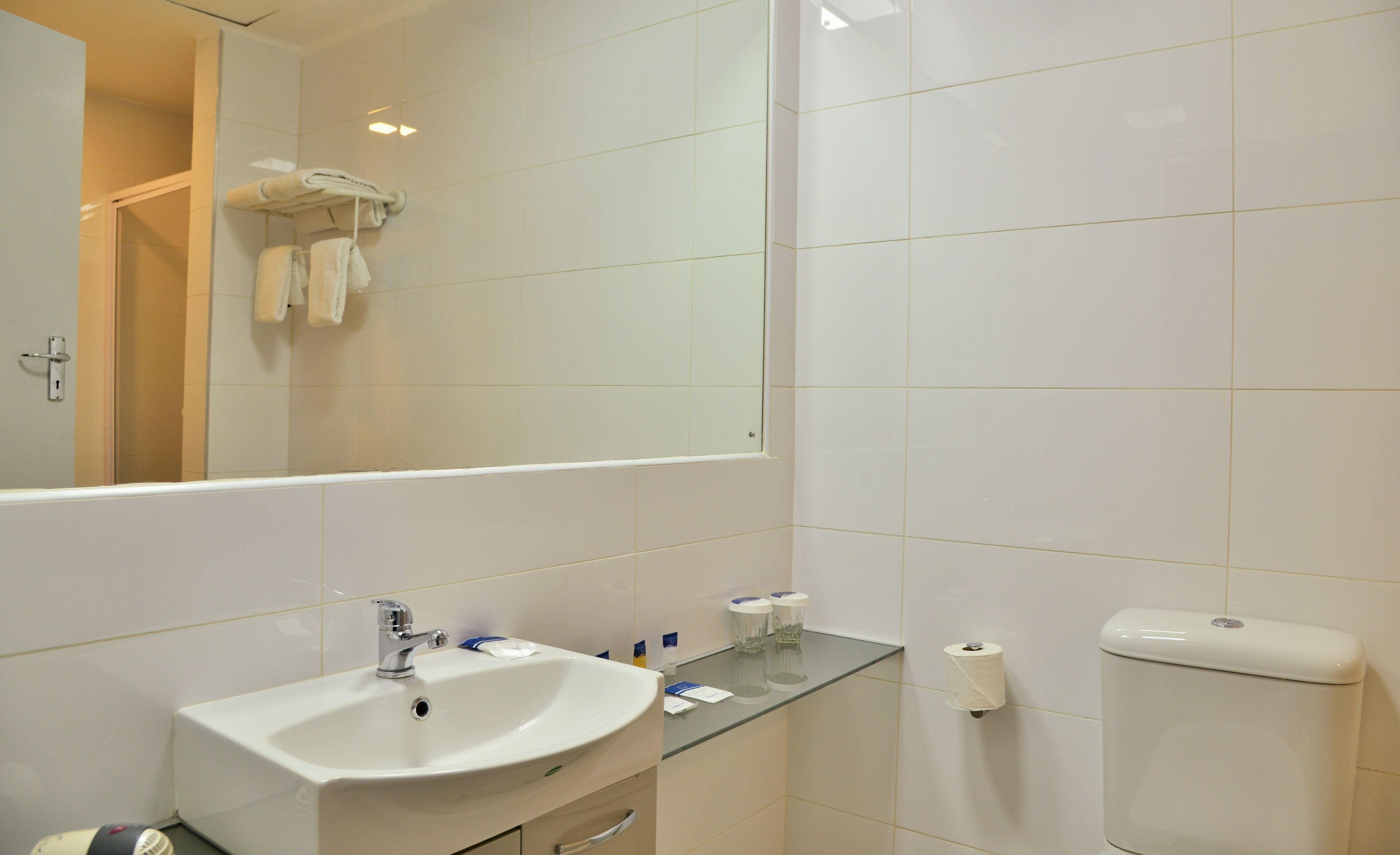 A bathroom with a sink, mirror, toilet, and towel rack.