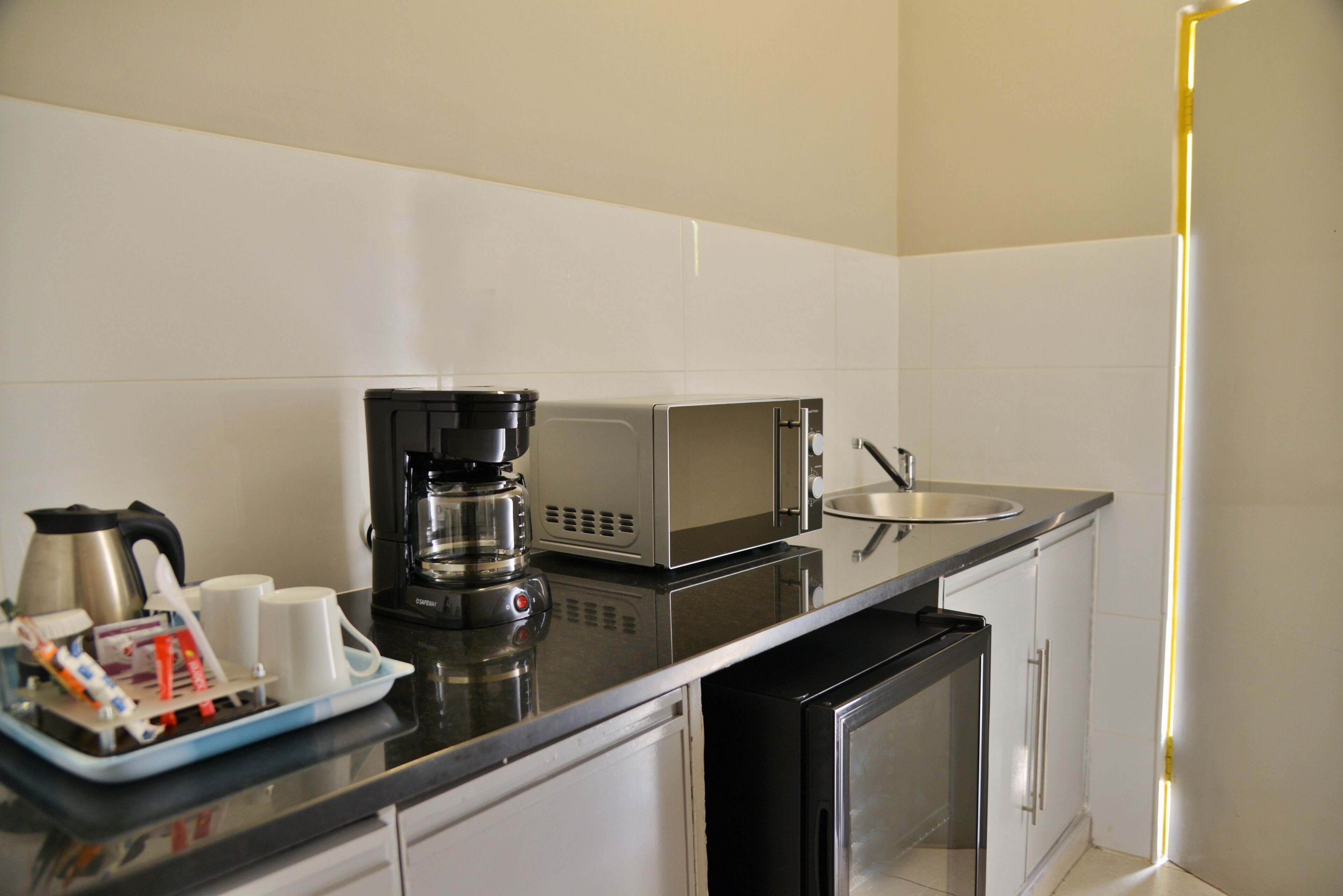 A modern kitchen with a coffee maker, microwave, and stainless steel appliances.
