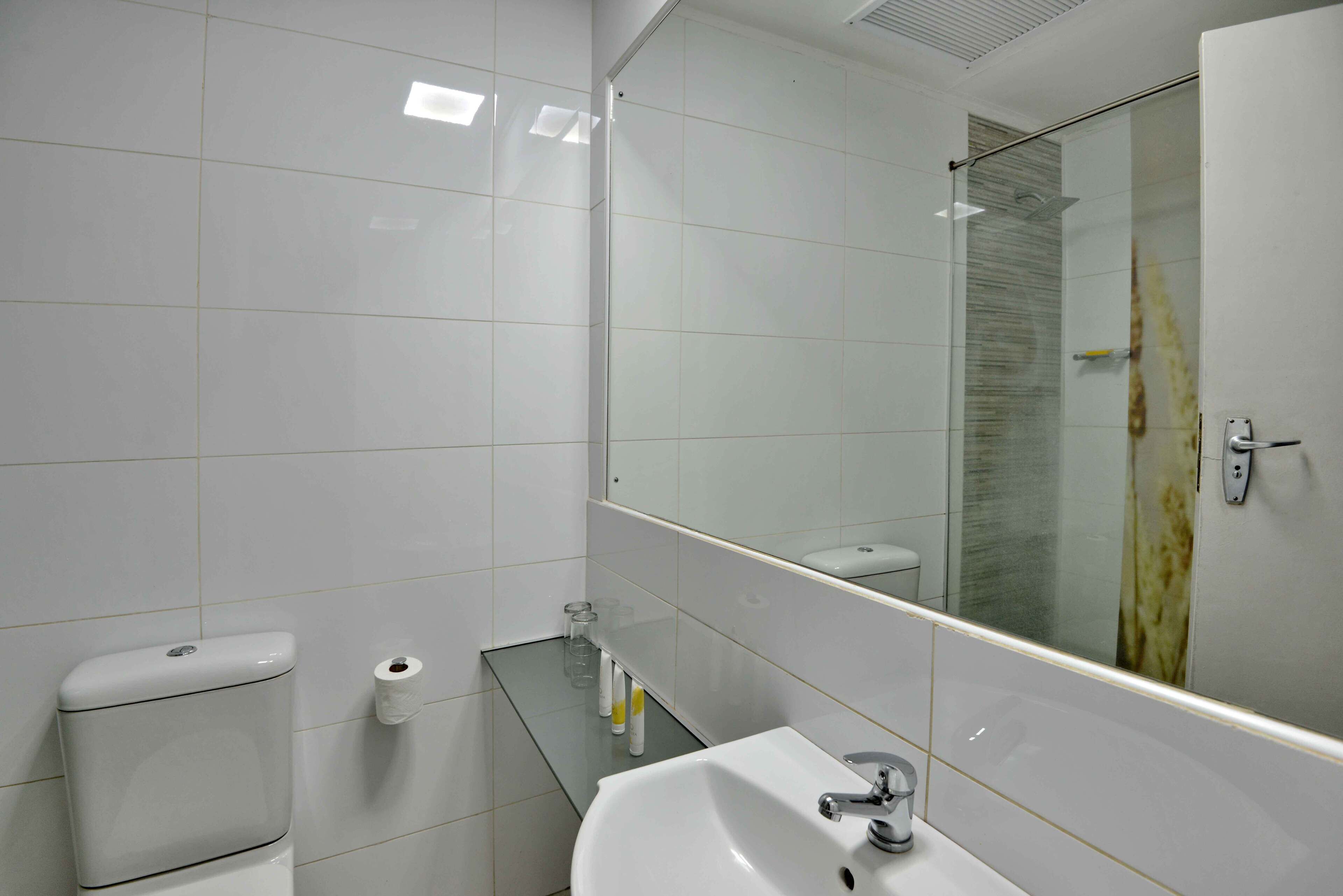 A modern bathroom with a white sink, toilet, and glass shower enclosure.