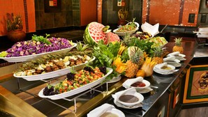 A buffet with various dishes and a watermelon centerpiece.
