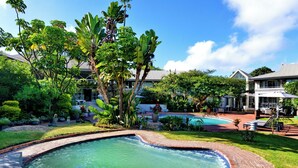 Una piscina rodeada de abundante vegetación y un jardín bien cuidado.