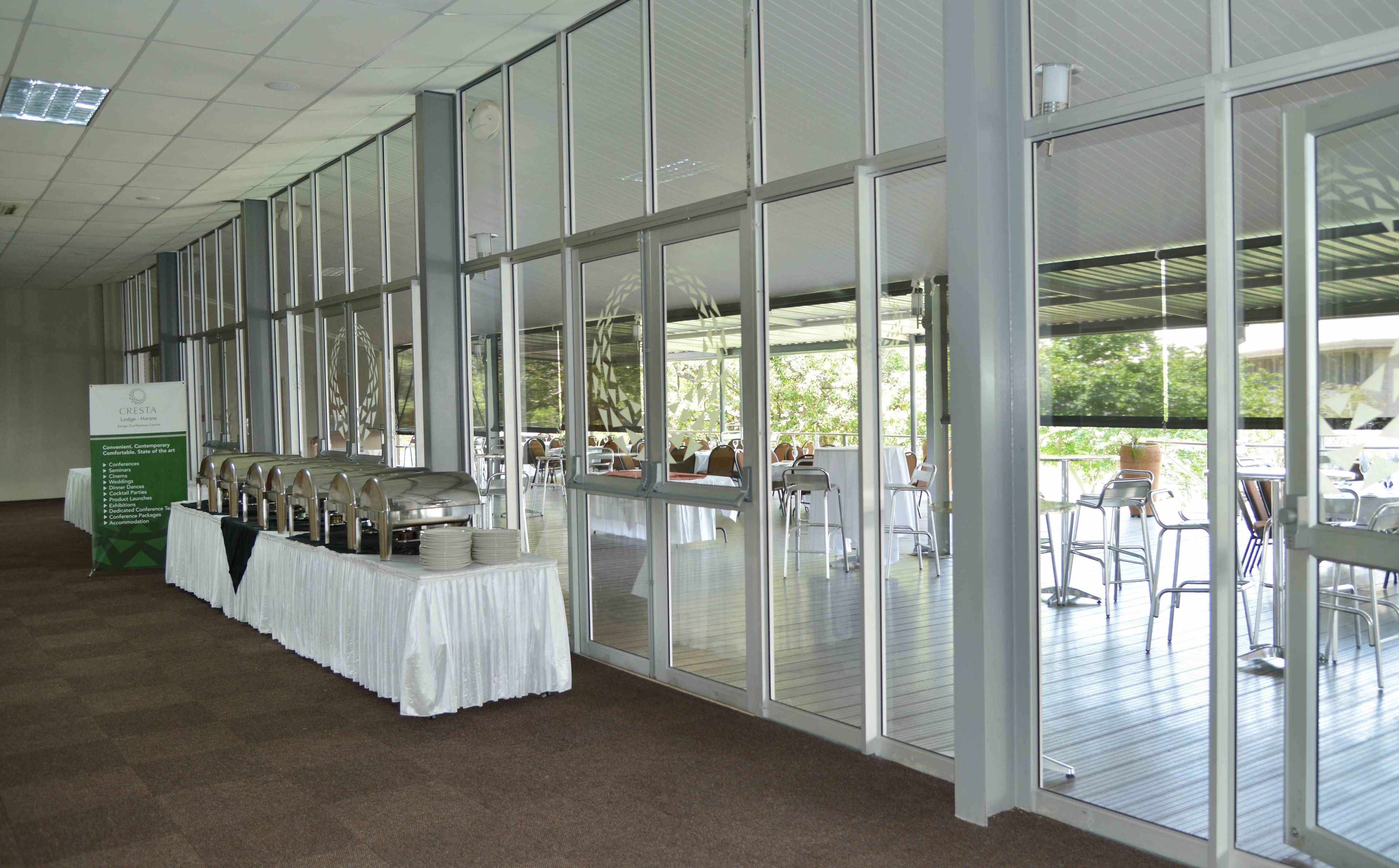 A spacious indoor area with a long table set up for dining, large windows, and a view of the outdoors.