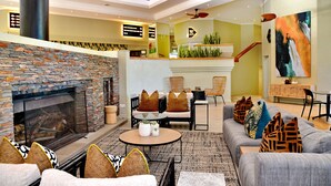 Amplia sala de estar con chimenea de piedra, asientos cómodos y una escalera moderna.