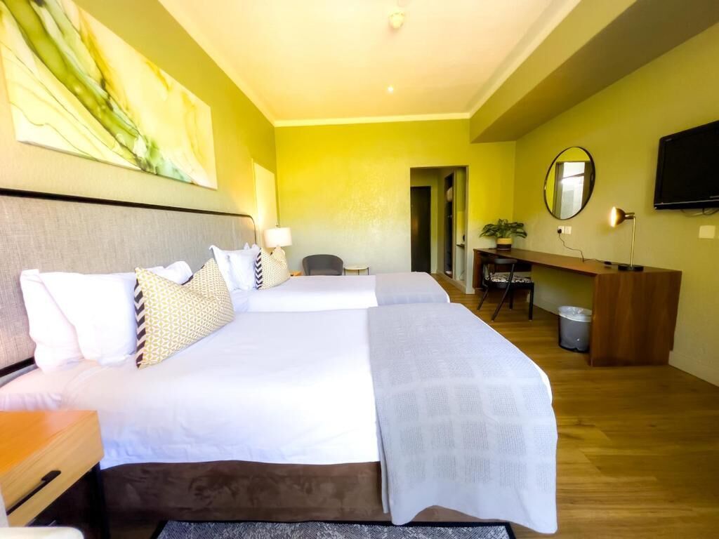 Une chambre d’hôtel avec un grand lit, un bureau, une chaise, une télévision et un miroir.