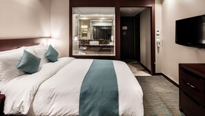 A hotel room with a large bed, a television, a bathroom with a mirror, and a carpeted floor. - Hotel Sunshine Seoul (Seoul)