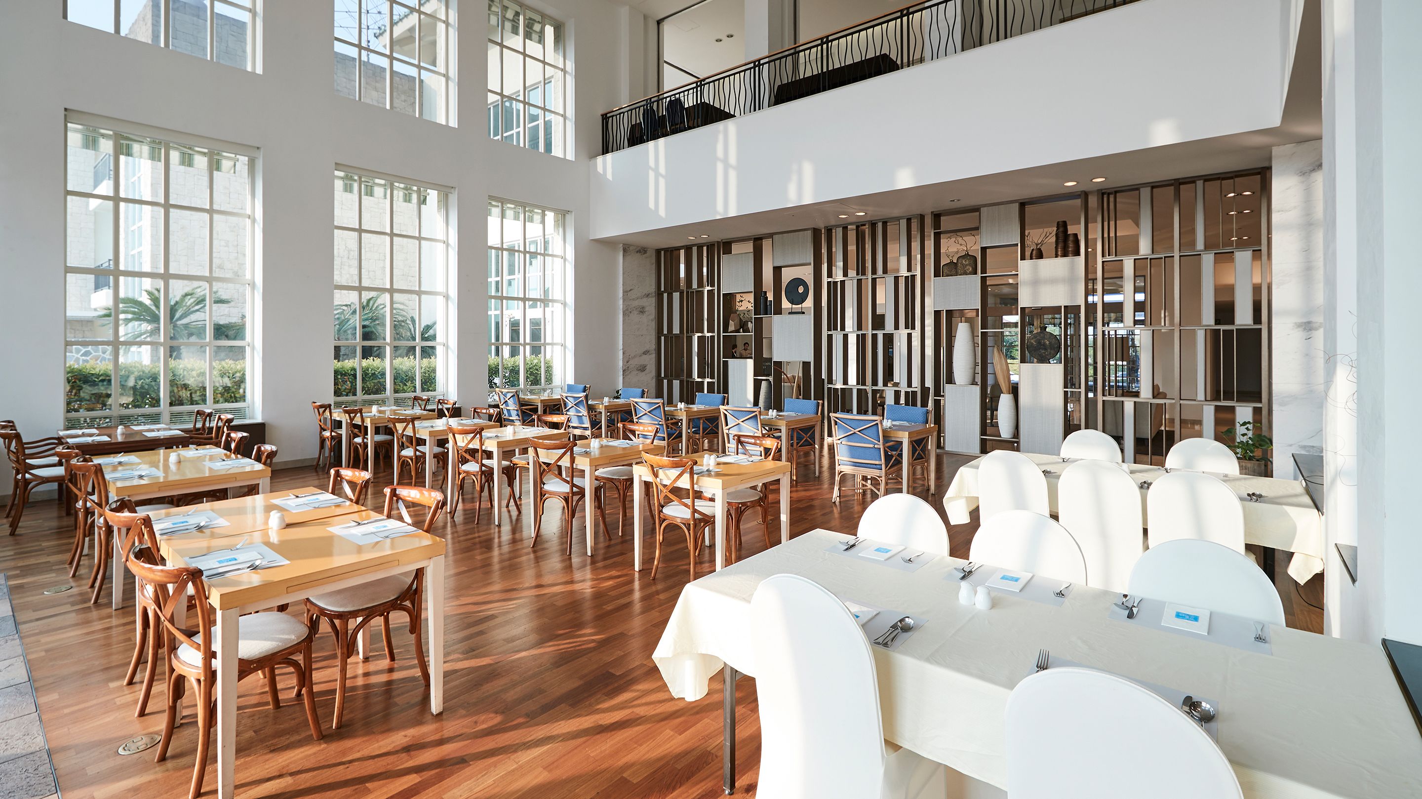 A spacious dining area with high ceilings, large windows, and a modern interior design.