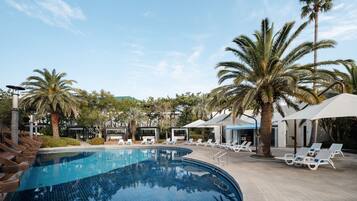 A swimming pool with lounge chairs and palm trees.