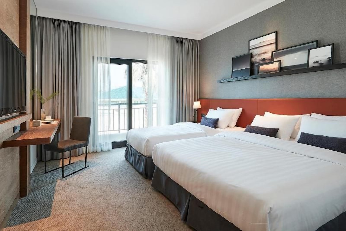 Une chambre d’hôtel avec deux lits, un bureau et une télévision.