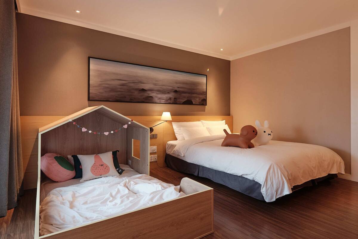 A hotel room with two beds, a wooden headboard, a painting on the wall, and a lamp.