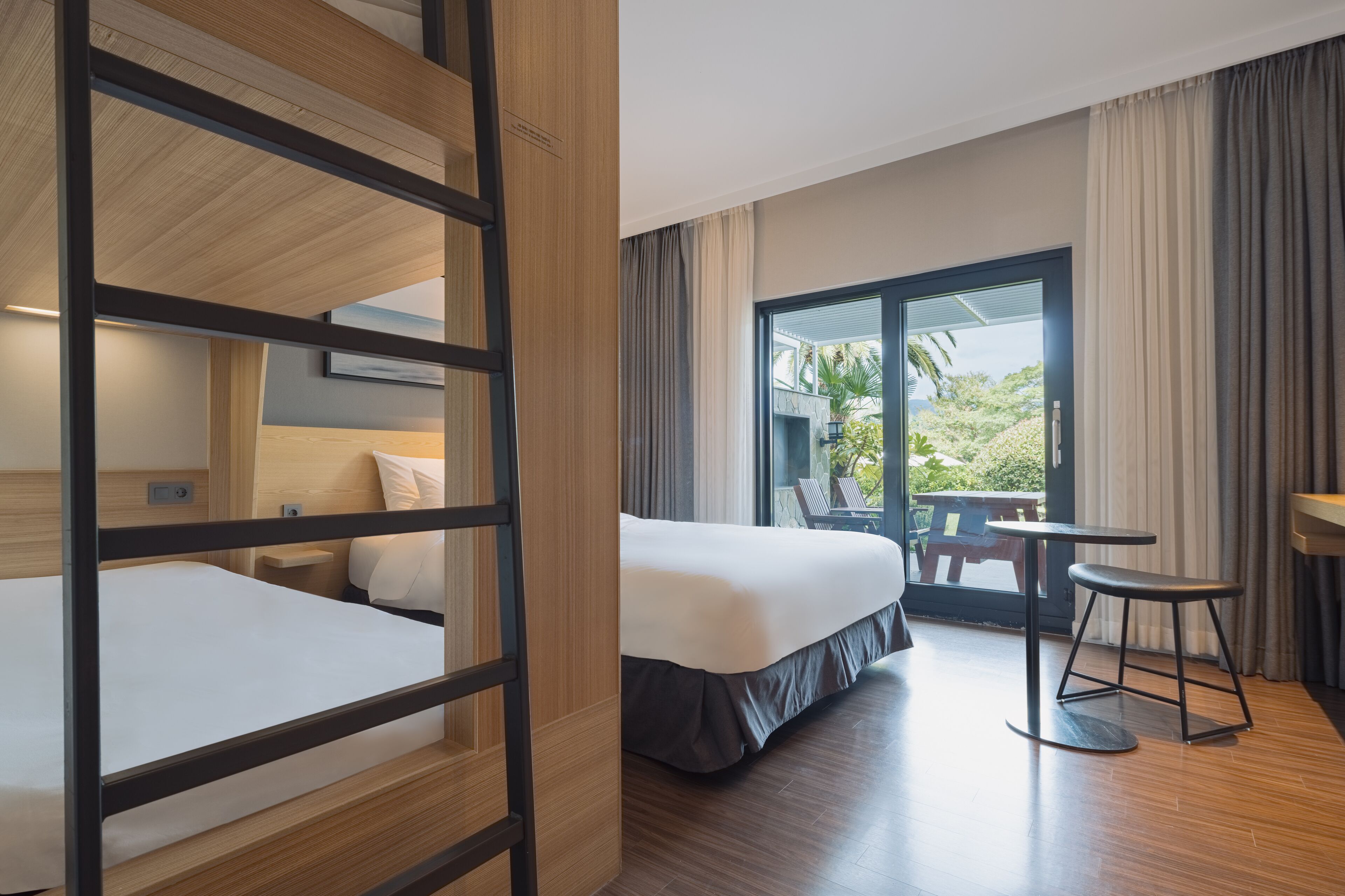 A hotel room with a bed, a desk, and a view of the outdoors.