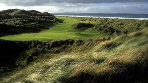 Un campo de golf costero con colinas ondulantes y vista al océano.