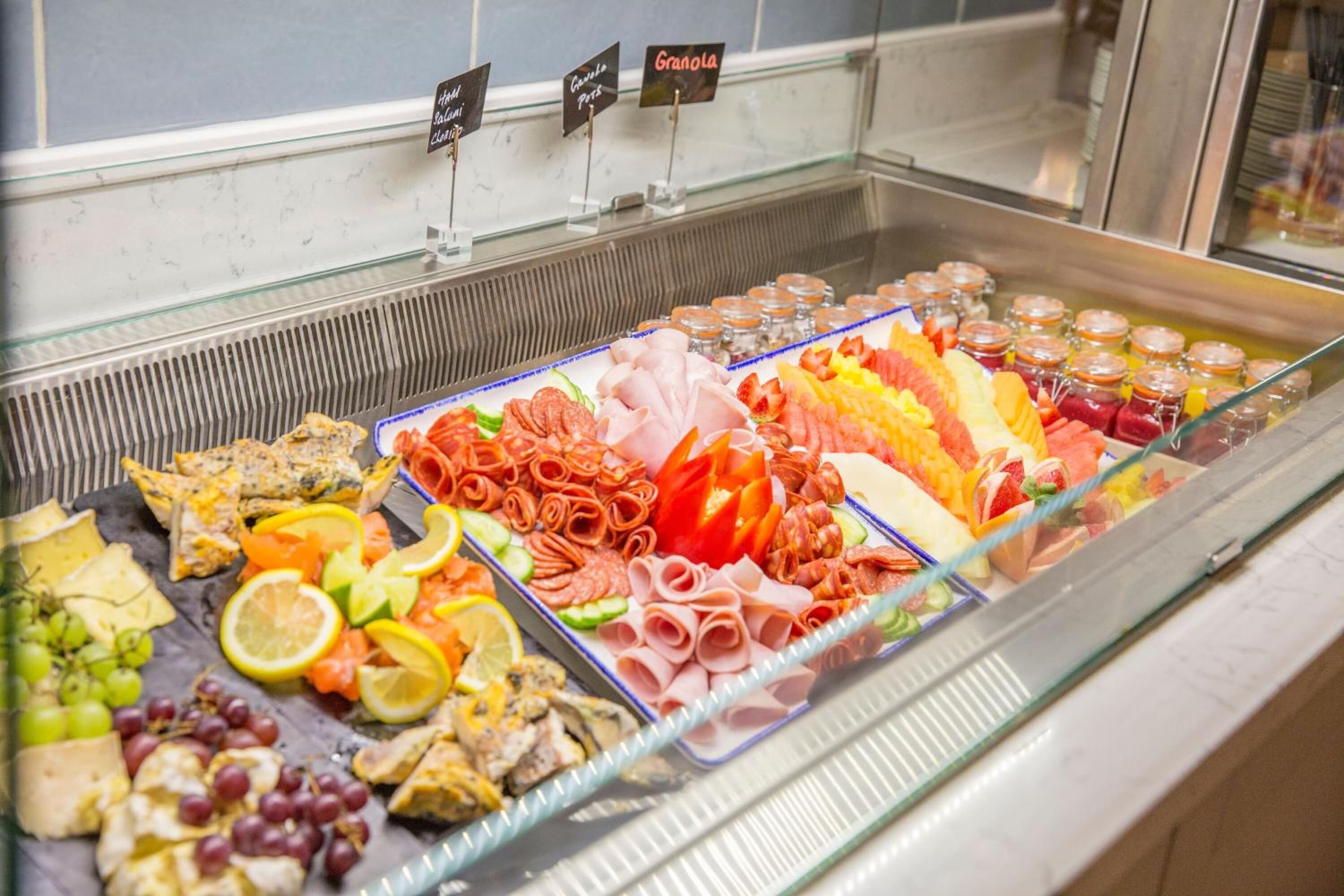 Un présentoir de charcuterie proposant une variété de viandes, de fromages et de fruits.
