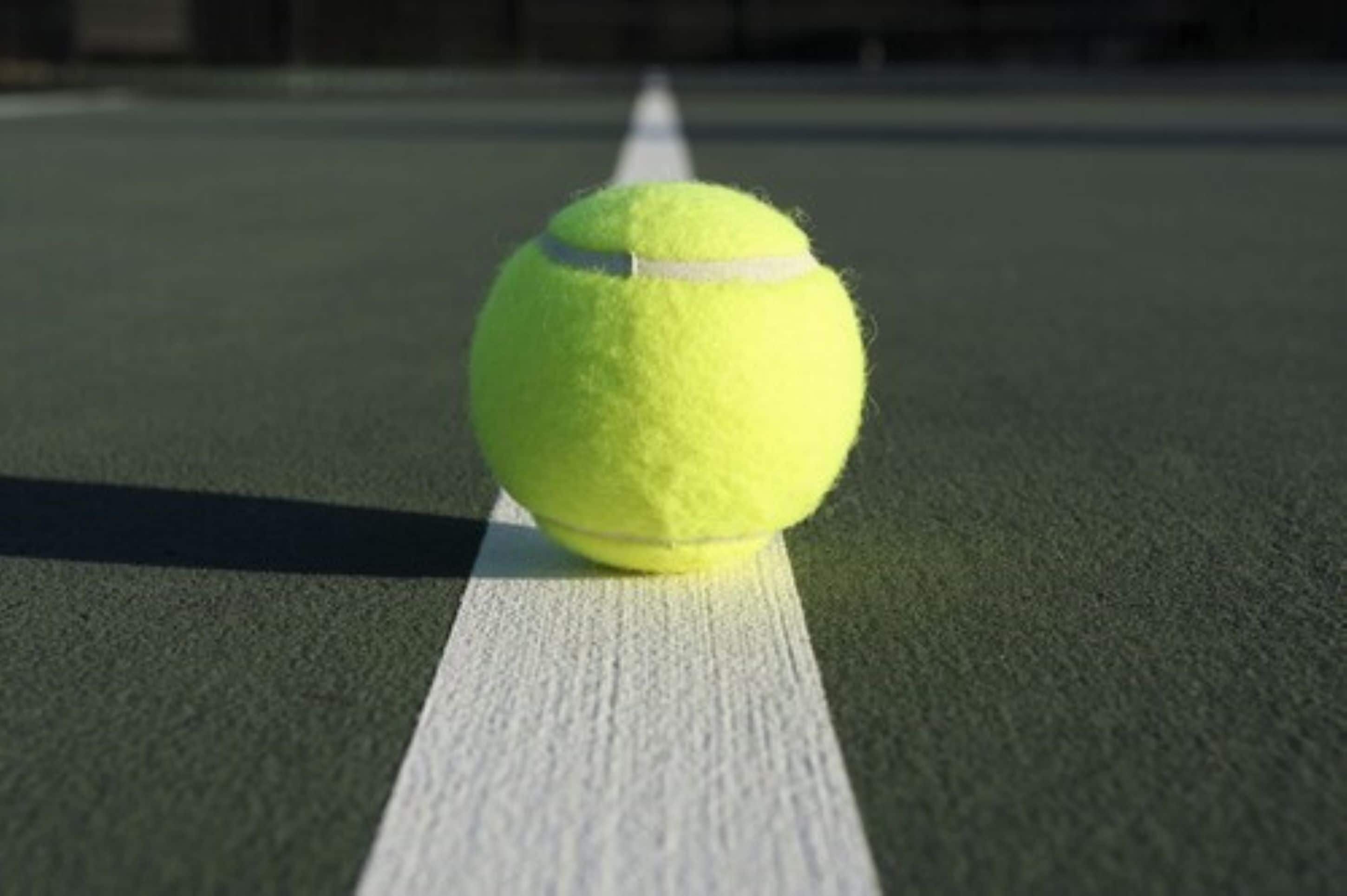 A tennis ball on a green court with white lines.