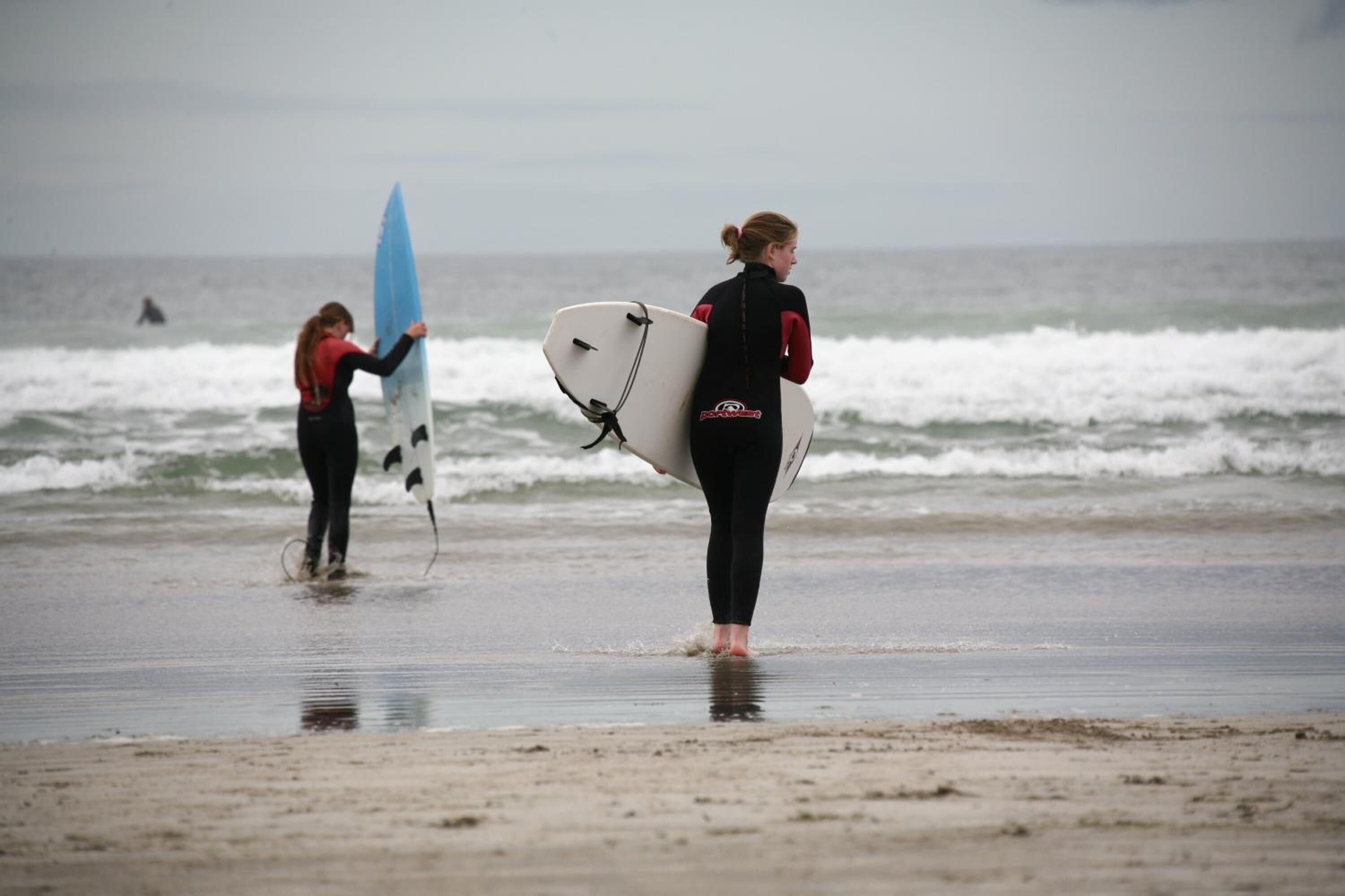 Deux personnes transportant des planches de surf sur une plage.