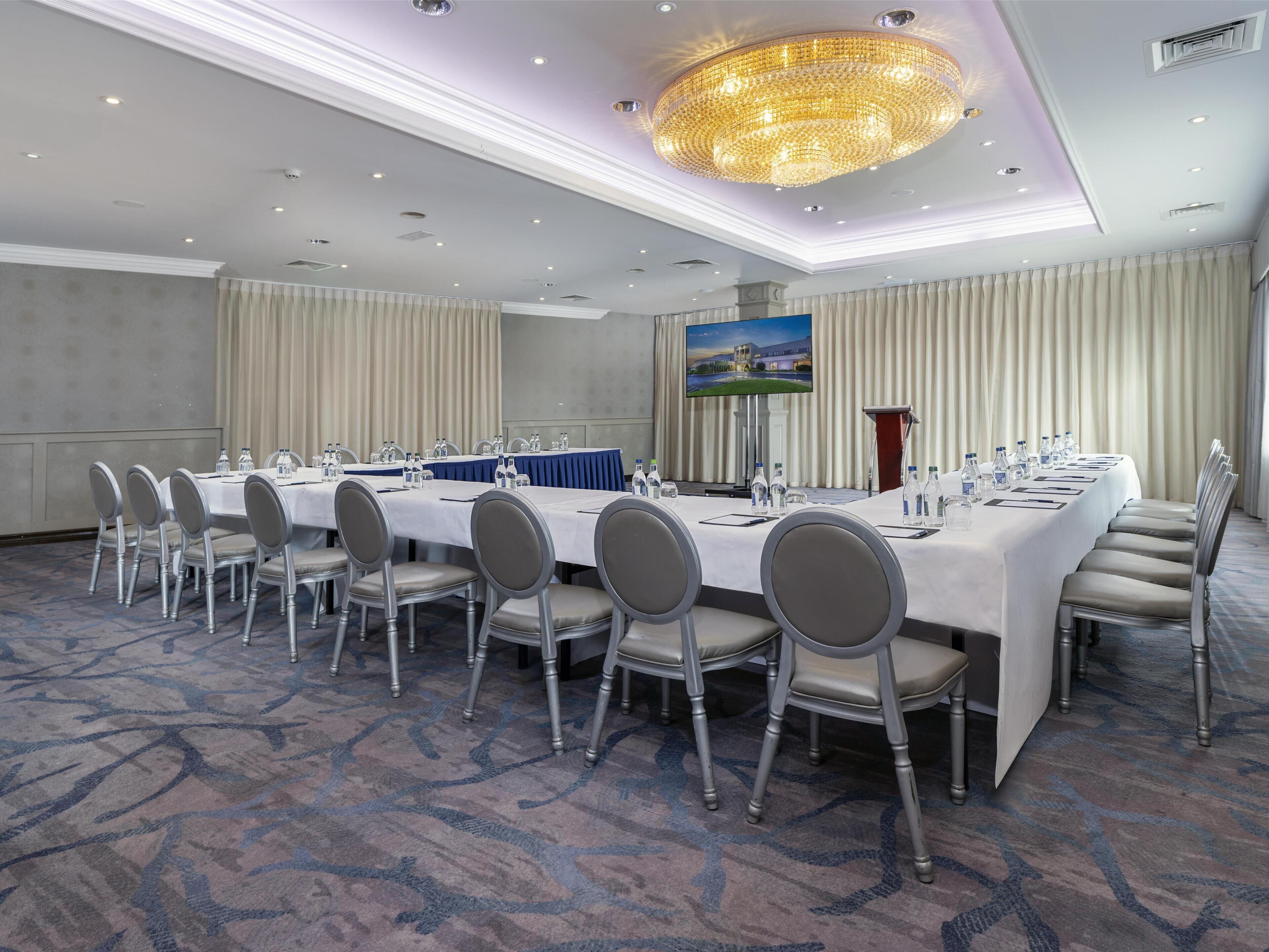 A conference room with a long table, chairs, and a large chandelier.