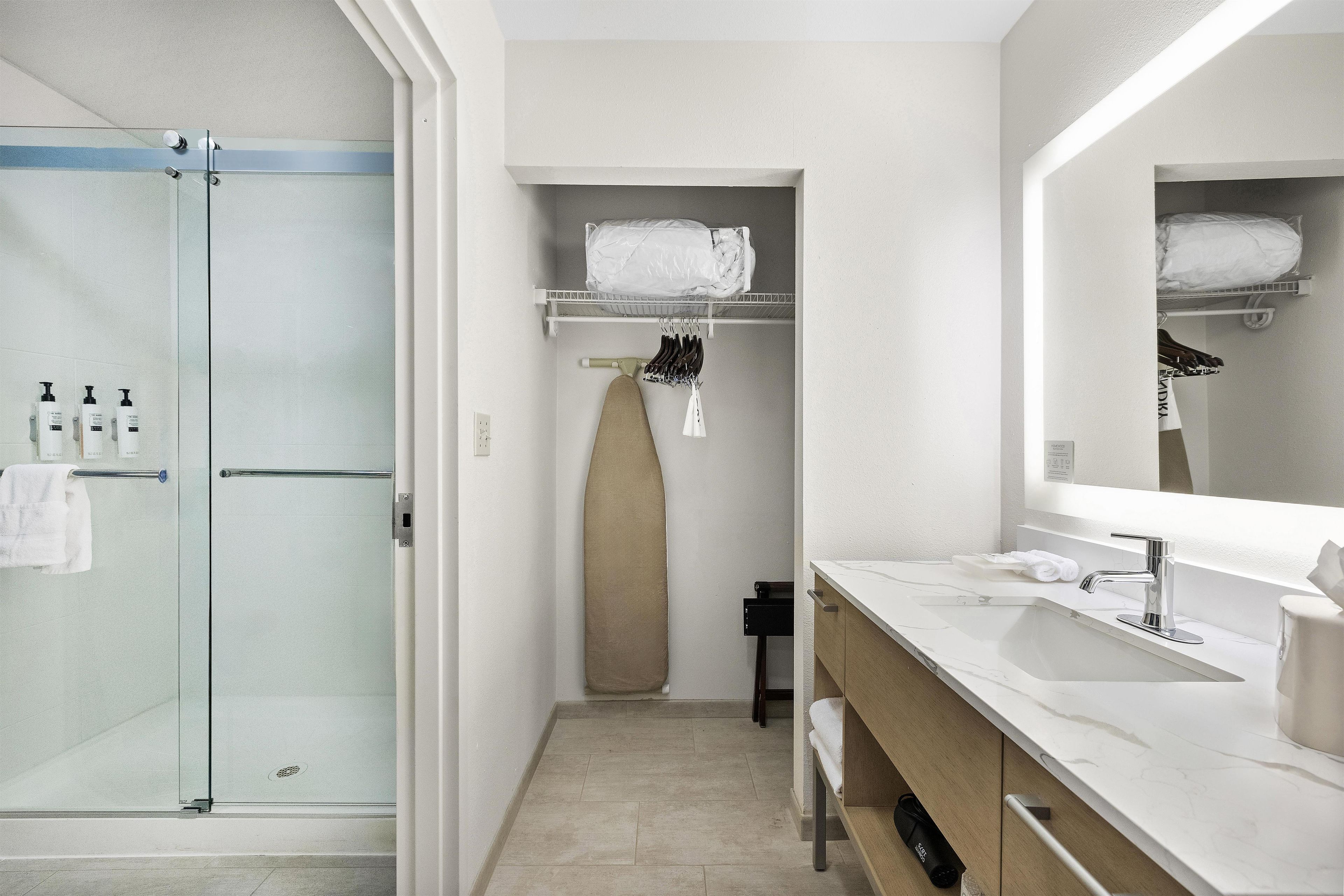 A modern bathroom with a glass shower enclosure, a white vanity with a large mirror, and a towel rack.