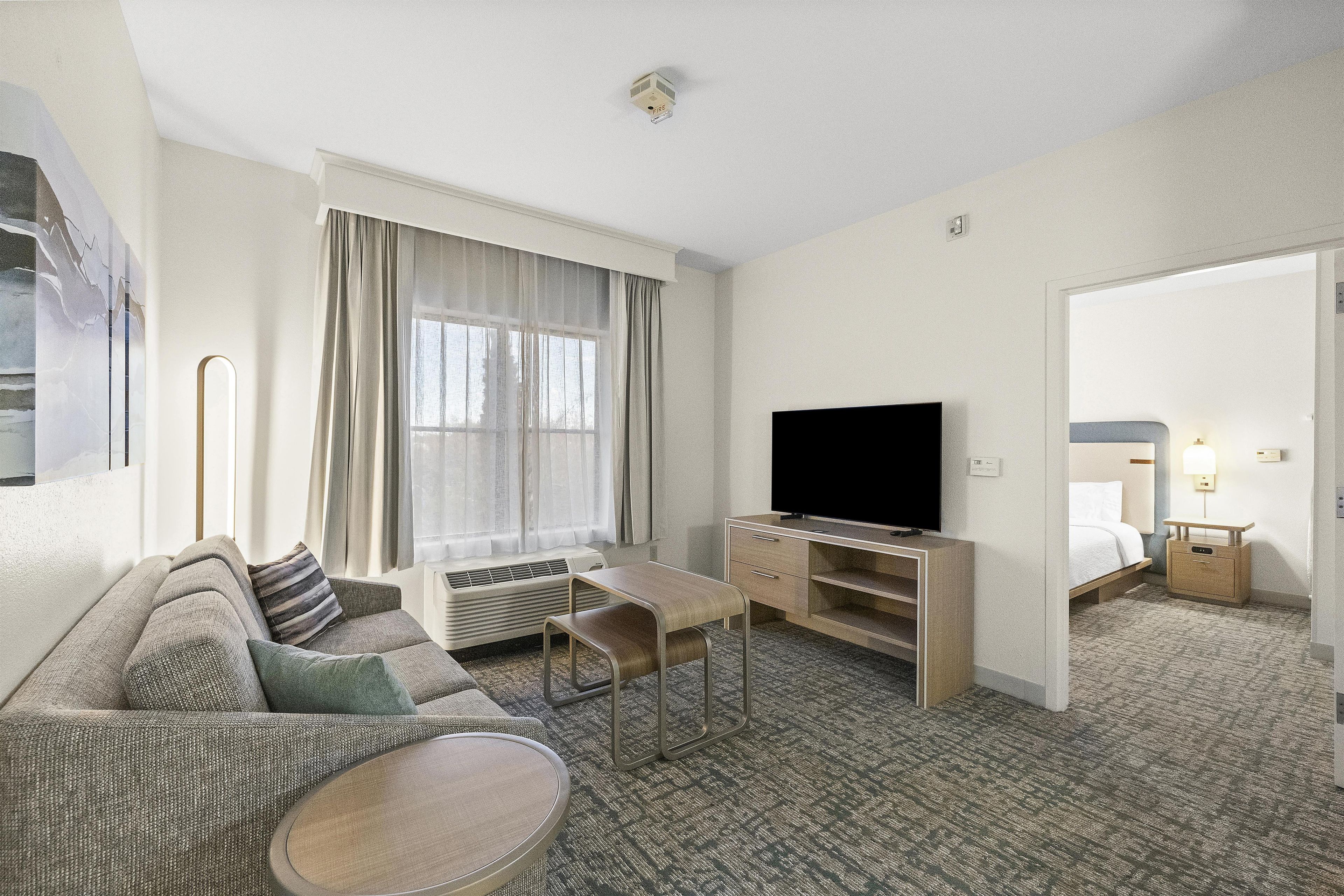 Una habitación de hotel con sofá, televisión, una mesita, escritorio y cama.