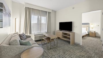 Una habitación de hotel con sofá, televisión, una mesita, escritorio y cama.