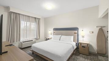 Een hotelkamer met een bed, bureau, televisie, verwarming en een raam met gordijnen.
