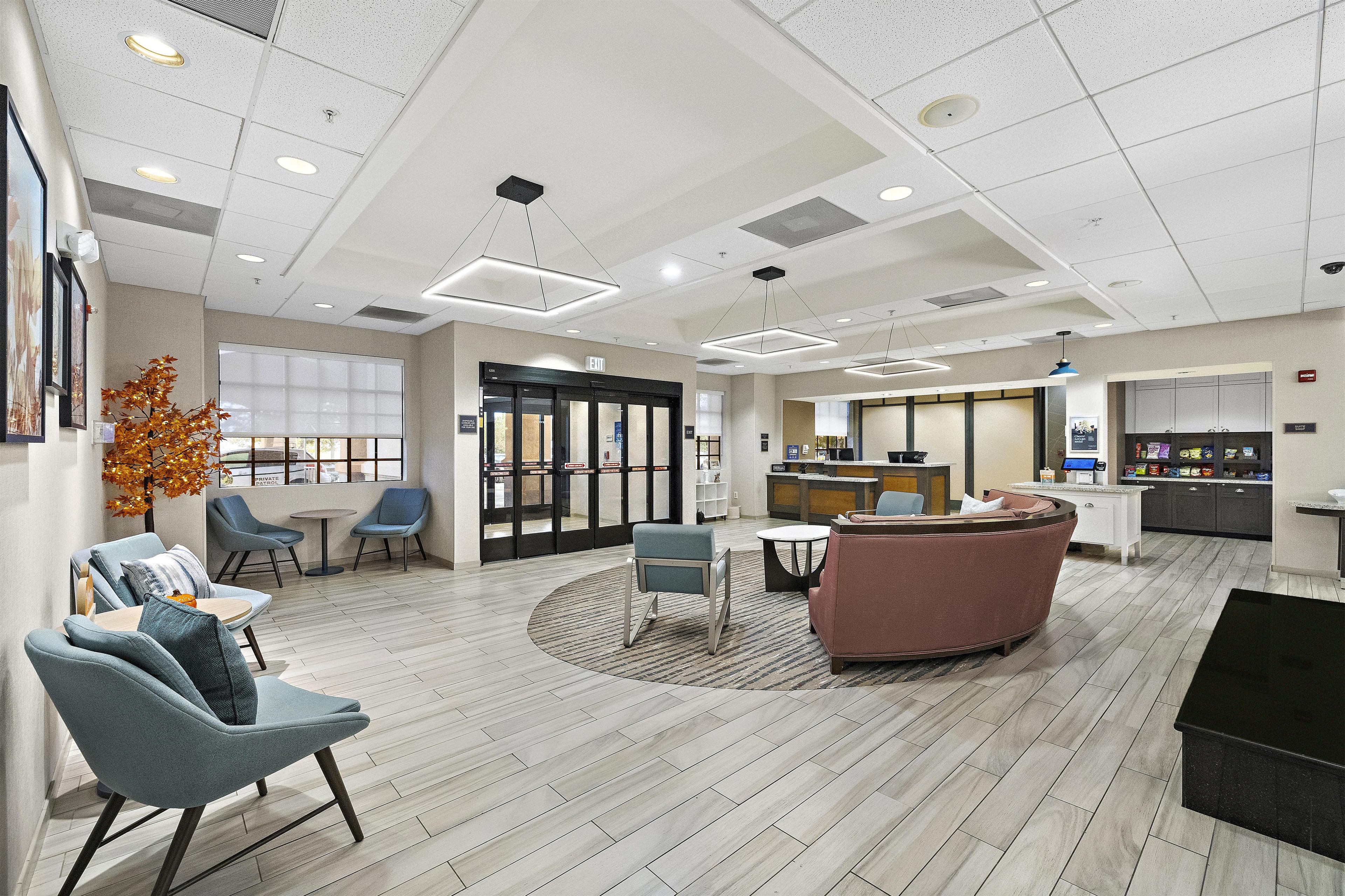 A hotel lobby with seating areas, a reception desk, and a kitchenette.