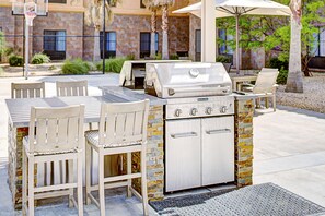 An outdoor kitchen with a grill, seating area, and a stone wall backdrop. - Homewood Suites by Hilton Lancaster (Lancaster)