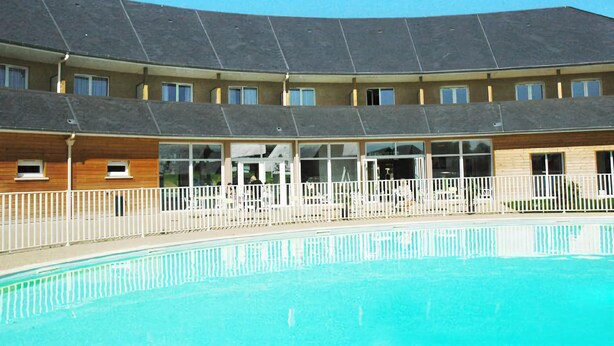 Un hotel con piscina, varios balcones y un espacio exterior cubierto.
