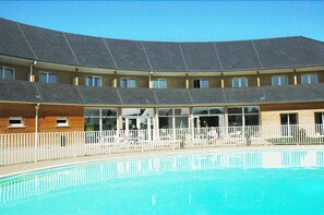 Un hotel con piscina, varios balcones y un espacio exterior cubierto.