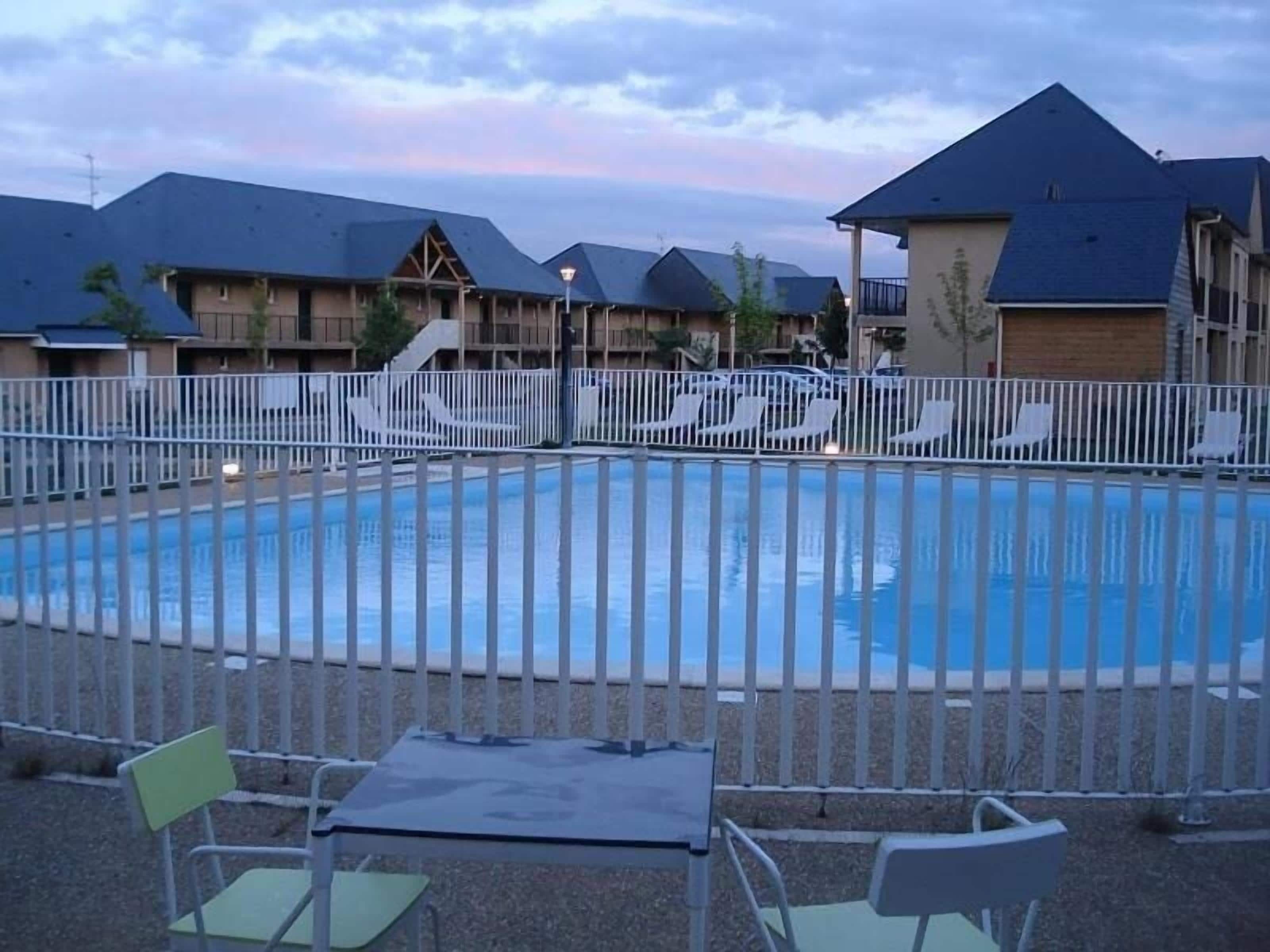 Een seizoensgebonden buitenzwembad, ligstoelen bij het zwembad