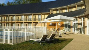 Un hotel con piscina, mobiliario exterior y un patio cubierto.