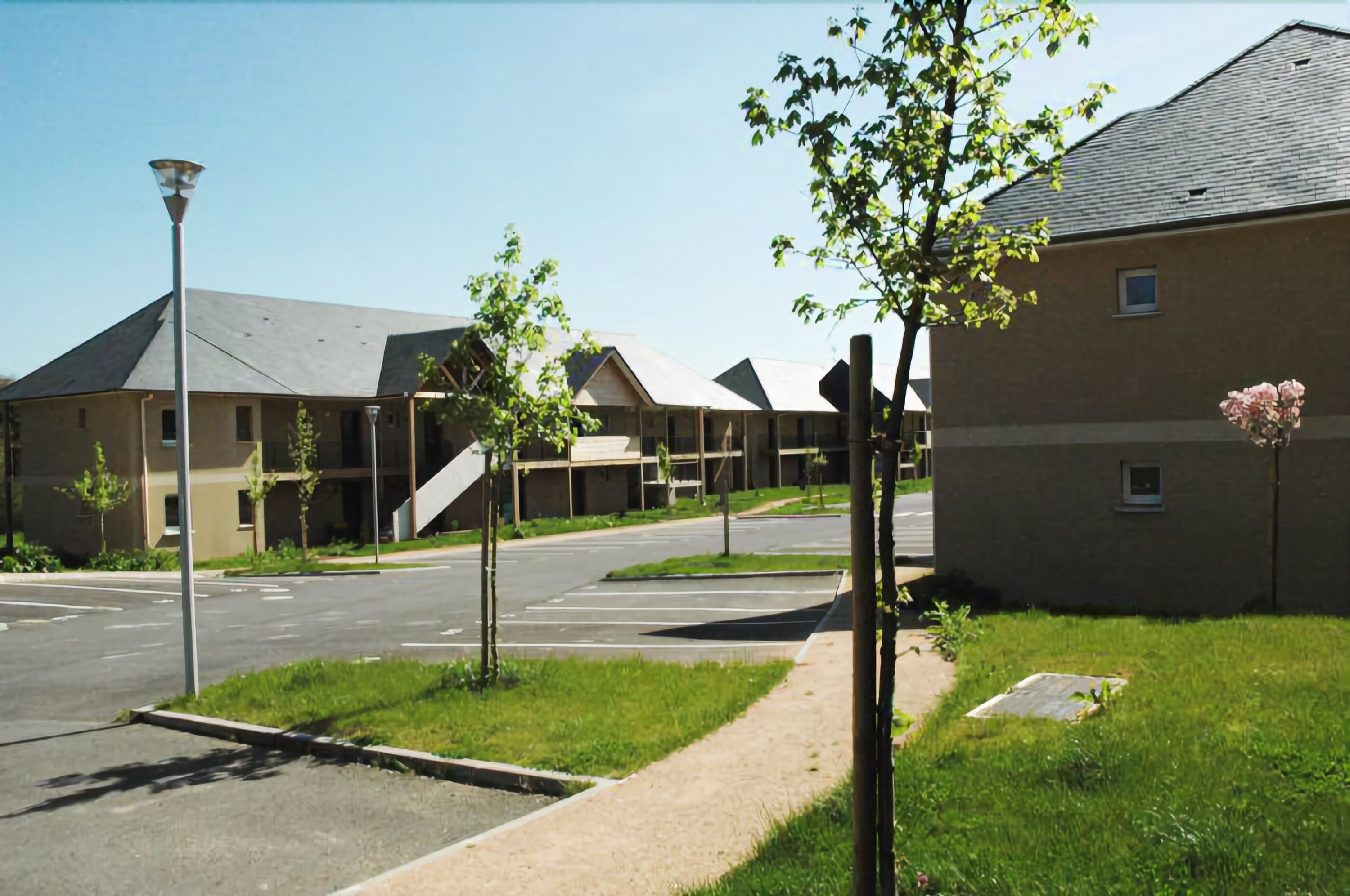 A modern building complex with multiple units, a parking area, and a pedestrian pathway.