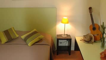Une chambre à coucher avec un lit, des oreillers, une lampe, une guitare et un tableau accroché au mur.