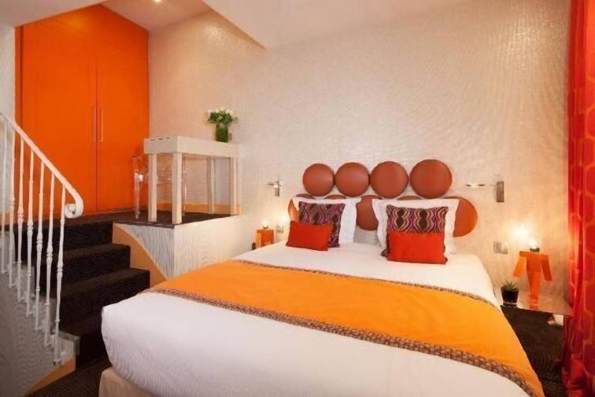 A bedroom with a bed, a staircase, a white cabinet, and a red curtain.