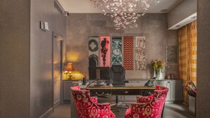 A modern dining area with a long table, two red upholstered chairs, a black office chair, and decorative wall art. - Hotel Le Petit Paris (Paris)