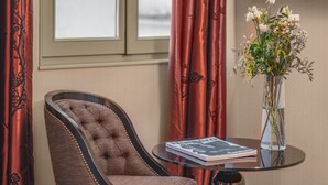 A tufted armchair, a glass table with a book, and a vase with flowers. - Hotel Le Petit Paris (Paris)