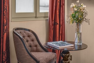 Un sillón con textura, una mesa de vidrio con un libro y un florero con flores.